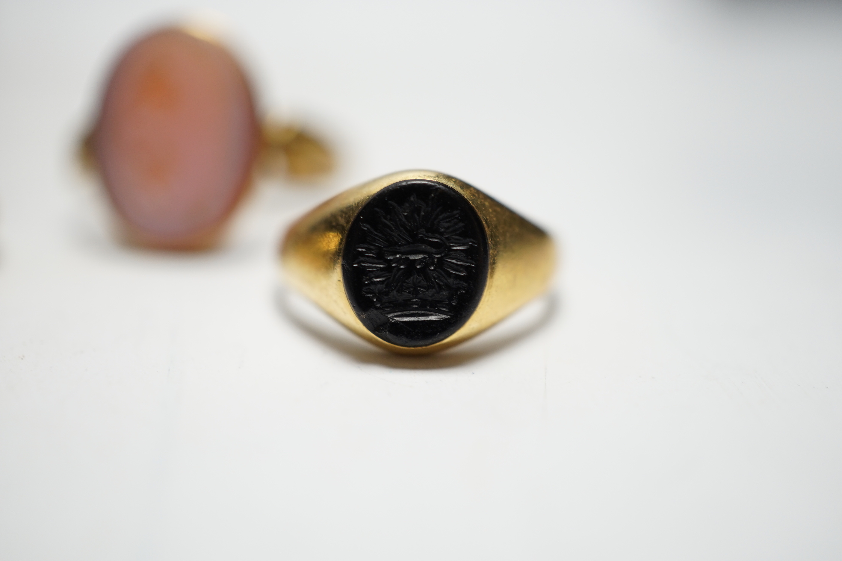 A Victorian yellow metal and sardonyx set oval seal ring, the matrix carved with two birds and motto, size O, together with two early 20th century yellow metal and chalcedony set child's signet rings, gross weight 9.7 gr